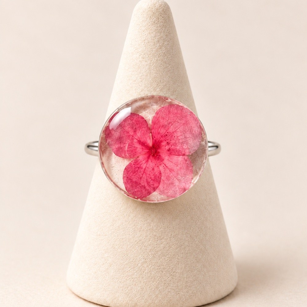 Anillo de plata con una flor rosa conservada en resina sobre un soporte