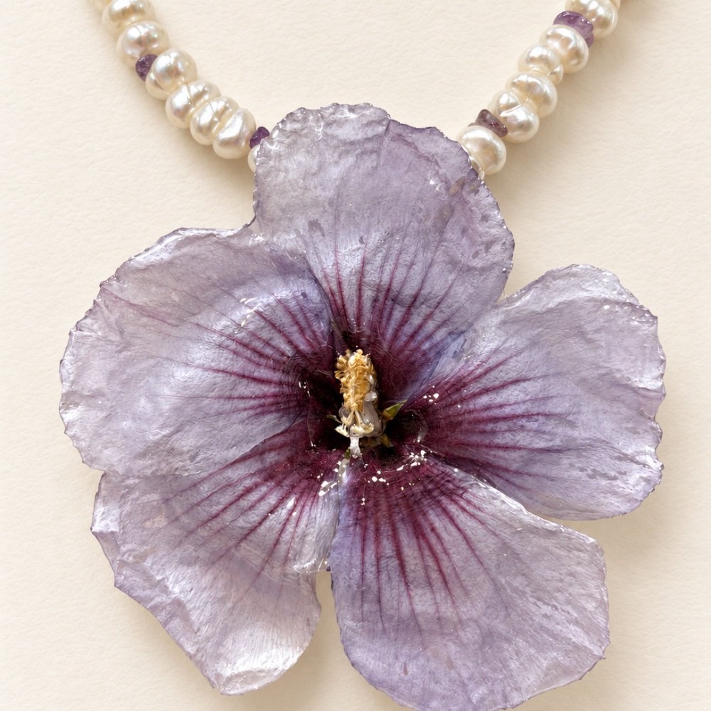 Colgante con una flor lila conservada en resina y perlas, en primer plano